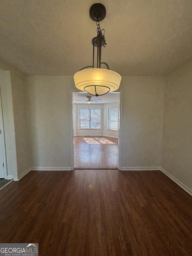 unfurnished dining area featuring a textured ceiling and dark hardwood / wood-style flooring