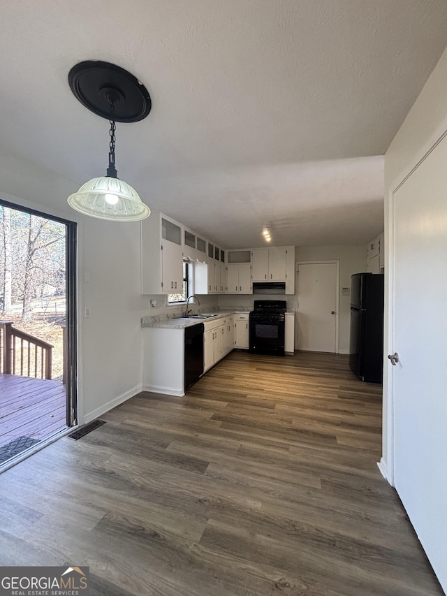 kitchen with pendant lighting, black appliances, dark hardwood / wood-style floors, and white cabinets