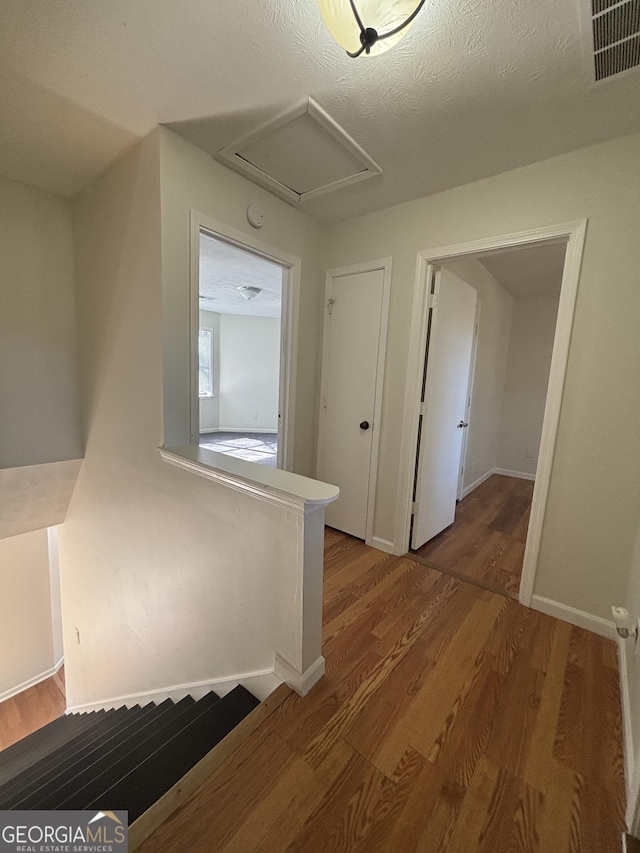 corridor with hardwood / wood-style flooring and a textured ceiling