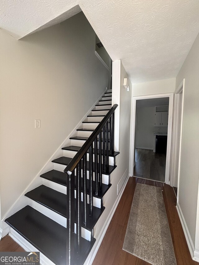 stairway featuring hardwood / wood-style floors and a textured ceiling