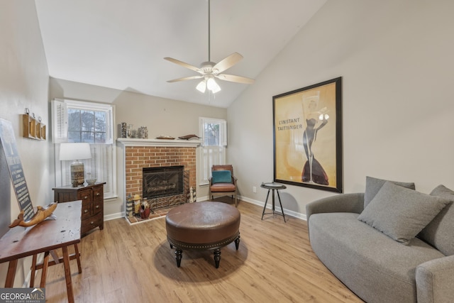 living room with vaulted ceiling, light wood-type flooring, ceiling fan, and a fireplace