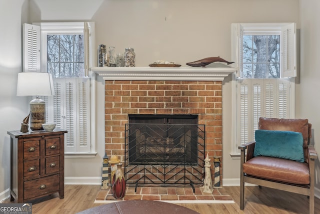 sitting room with a brick fireplace, a healthy amount of sunlight, and light wood-type flooring