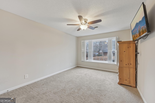 empty room featuring ceiling fan, carpet, and a textured ceiling