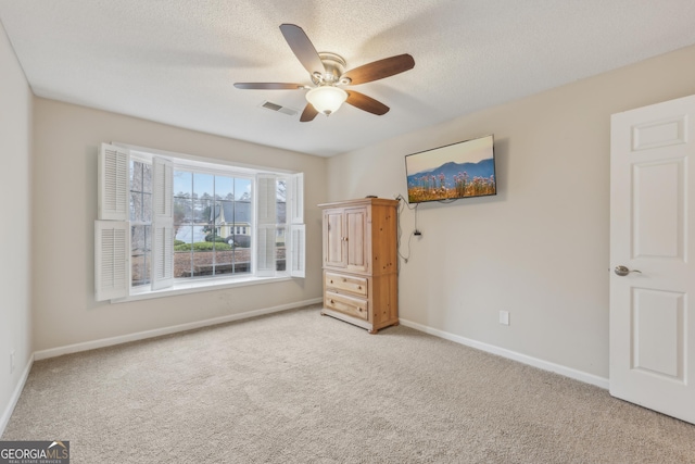 unfurnished bedroom with ceiling fan, carpet floors, and a textured ceiling