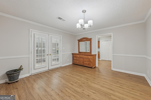 unfurnished room with french doors, crown molding, a textured ceiling, light wood-type flooring, and a notable chandelier