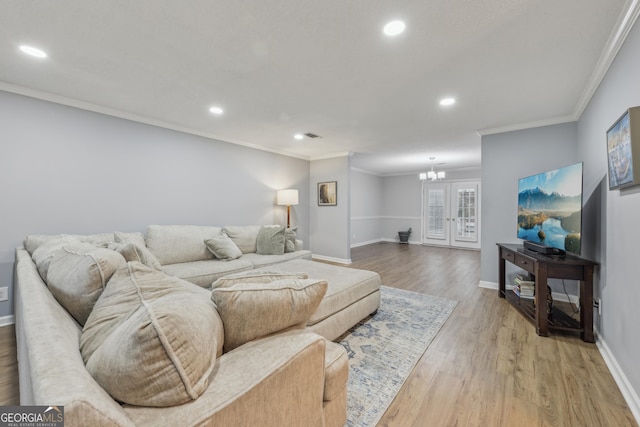 living room with a notable chandelier, crown molding, and light hardwood / wood-style floors