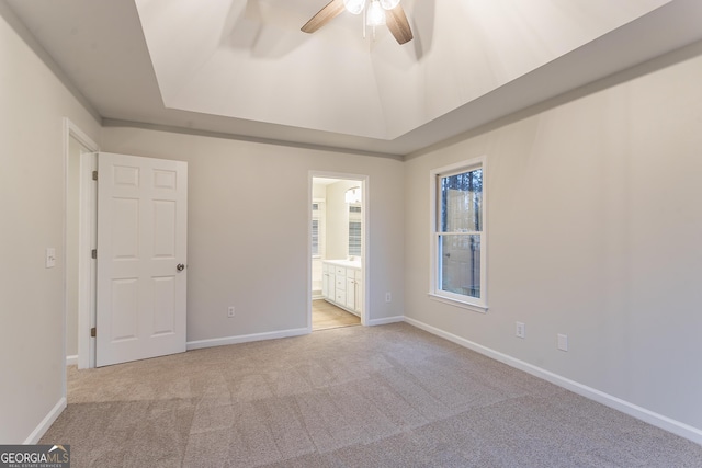 carpeted empty room featuring a raised ceiling and ceiling fan