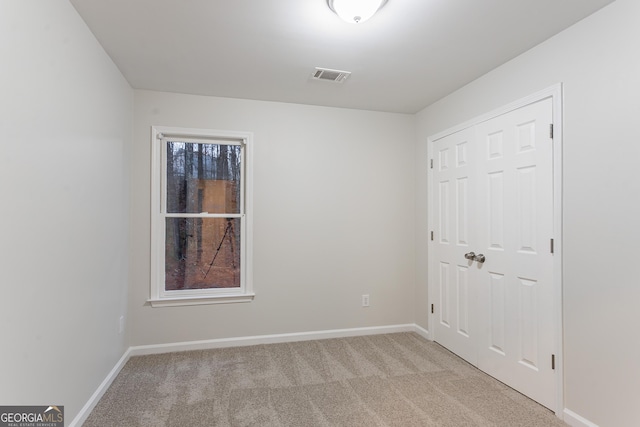 unfurnished bedroom with light carpet and a closet