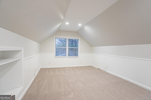 additional living space featuring vaulted ceiling and light carpet