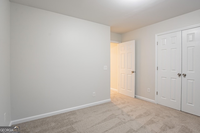 unfurnished bedroom featuring light carpet and a closet