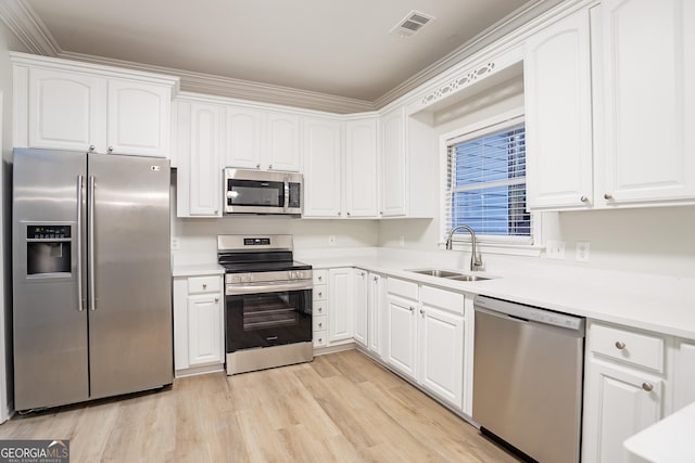 kitchen featuring white cabinetry, sink, light hardwood / wood-style floors, and appliances with stainless steel finishes