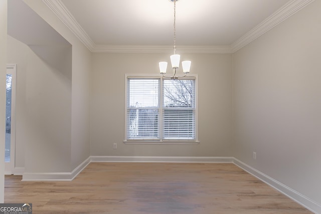 unfurnished dining area with an inviting chandelier, crown molding, and light hardwood / wood-style flooring