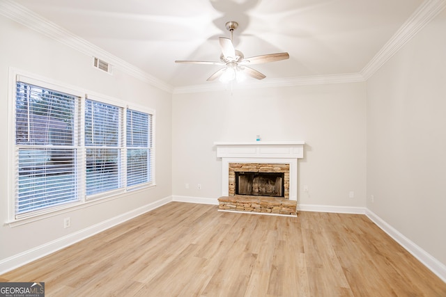 unfurnished living room featuring ornamental molding, a stone fireplace, ceiling fan, and light hardwood / wood-style floors