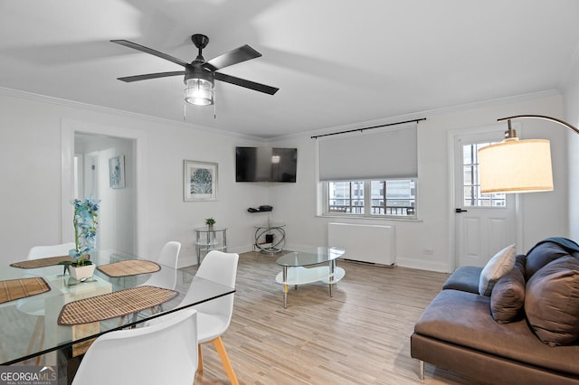 living room featuring ornamental molding, radiator heating unit, light hardwood / wood-style flooring, and a wealth of natural light