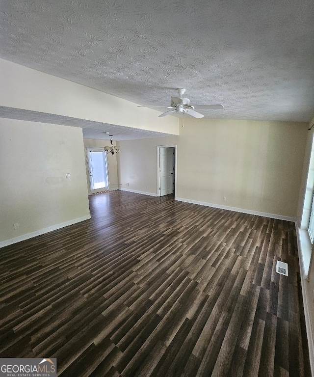 unfurnished living room with dark hardwood / wood-style flooring, ceiling fan with notable chandelier, and a textured ceiling