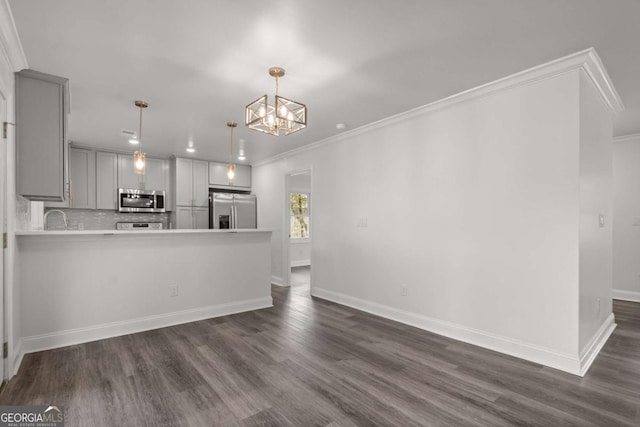 kitchen with appliances with stainless steel finishes, dark hardwood / wood-style floors, gray cabinets, kitchen peninsula, and pendant lighting