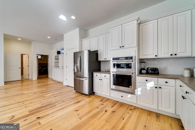 kitchen featuring tasteful backsplash, light hardwood / wood-style flooring, stainless steel appliances, and white cabinets