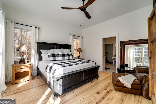 bedroom featuring lofted ceiling, light hardwood / wood-style floors, and multiple windows