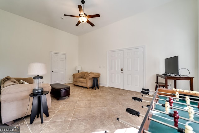 living room featuring light tile patterned floors, ceiling fan, and a high ceiling