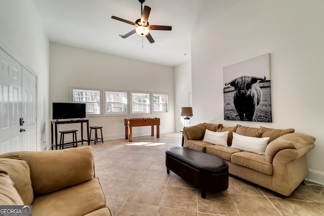 tiled living room featuring ceiling fan and a towering ceiling