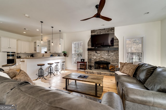 living room with light hardwood / wood-style flooring, a fireplace, a wealth of natural light, and ceiling fan