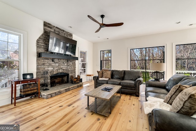 living room with a fireplace, light hardwood / wood-style floors, and ceiling fan