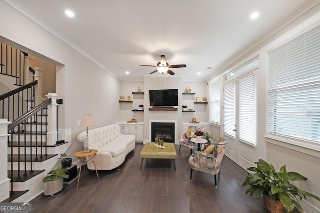 living room with wood-type flooring, ornamental molding, and ceiling fan