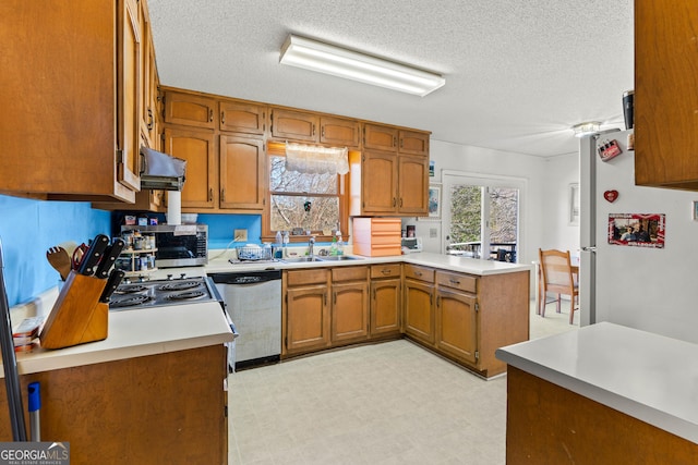 kitchen featuring sink, ventilation hood, a textured ceiling, kitchen peninsula, and stainless steel appliances