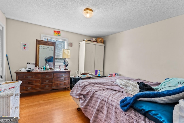 bedroom with light hardwood / wood-style flooring and a textured ceiling