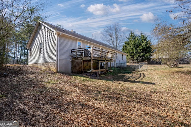 rear view of property featuring a wooden deck and a lawn