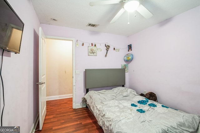 bedroom featuring ceiling fan, dark hardwood / wood-style floors, and a textured ceiling