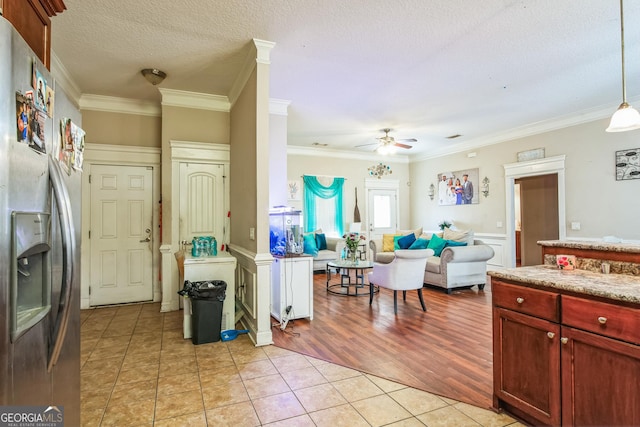 kitchen featuring crown molding, decorative light fixtures, light tile patterned floors, and stainless steel fridge with ice dispenser