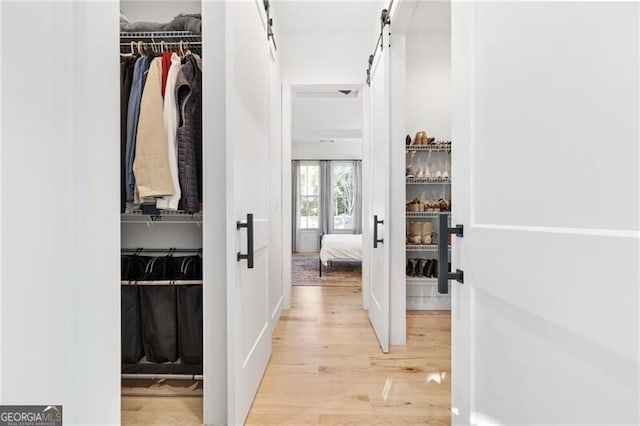 corridor with french doors, a barn door, and light wood-type flooring