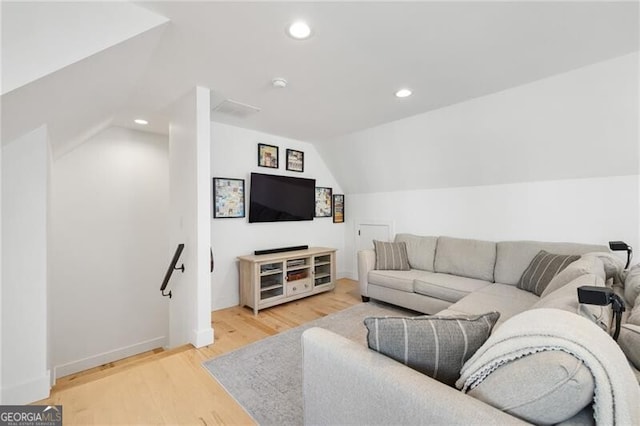 living room featuring lofted ceiling and light hardwood / wood-style floors