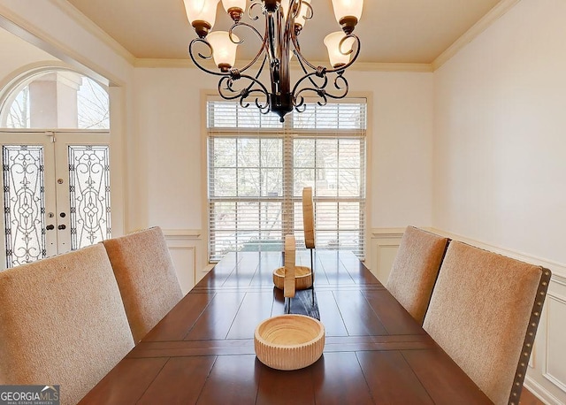 dining room featuring a decorative wall, french doors, an inviting chandelier, and ornamental molding