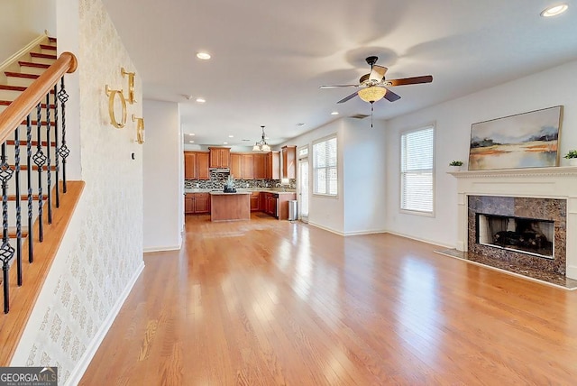 living room with a high end fireplace, stairway, light wood-style flooring, and recessed lighting