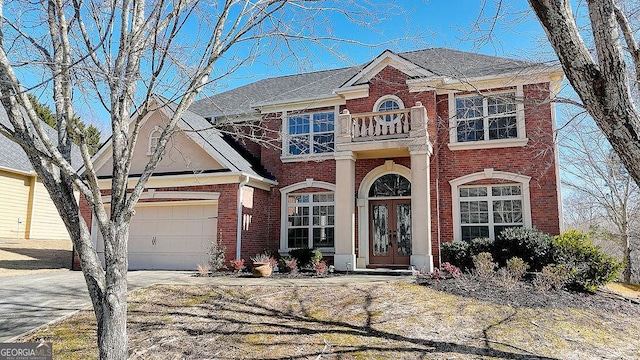 view of front of property with a balcony, driveway, an attached garage, french doors, and brick siding