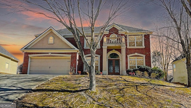 view of front of property with an attached garage, french doors, brick siding, and driveway