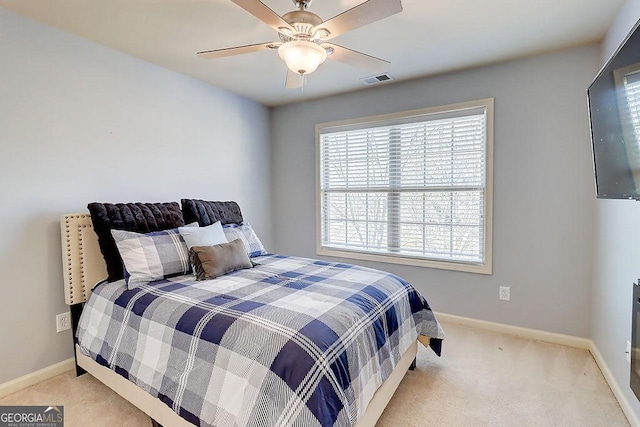 bedroom with visible vents, baseboards, light colored carpet, and a ceiling fan