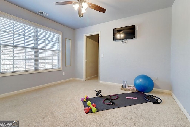 exercise area featuring visible vents, light carpet, baseboards, and ceiling fan