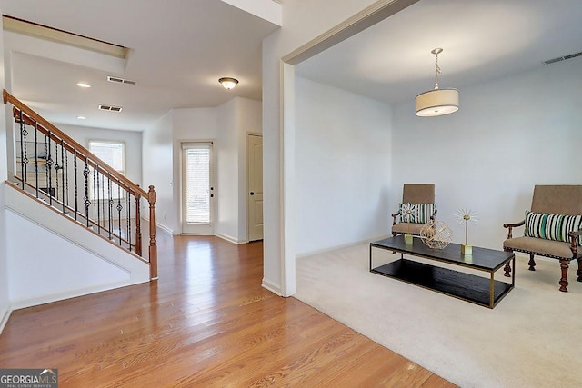 sitting room with stairway, wood finished floors, visible vents, and baseboards