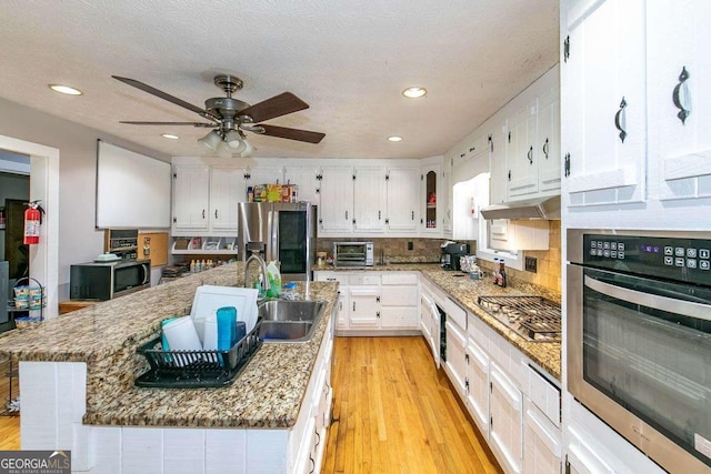 kitchen featuring appliances with stainless steel finishes, a center island with sink, and white cabinets