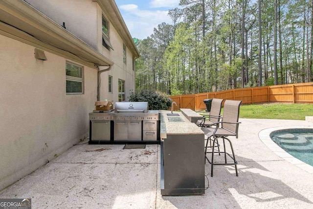 view of patio / terrace with area for grilling, a fenced in pool, and an outdoor wet bar