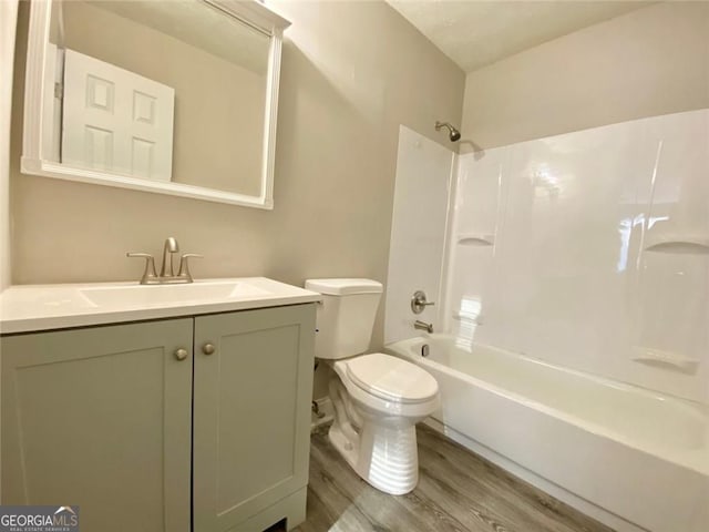 full bathroom with hardwood / wood-style flooring, bathing tub / shower combination, vanity, and toilet