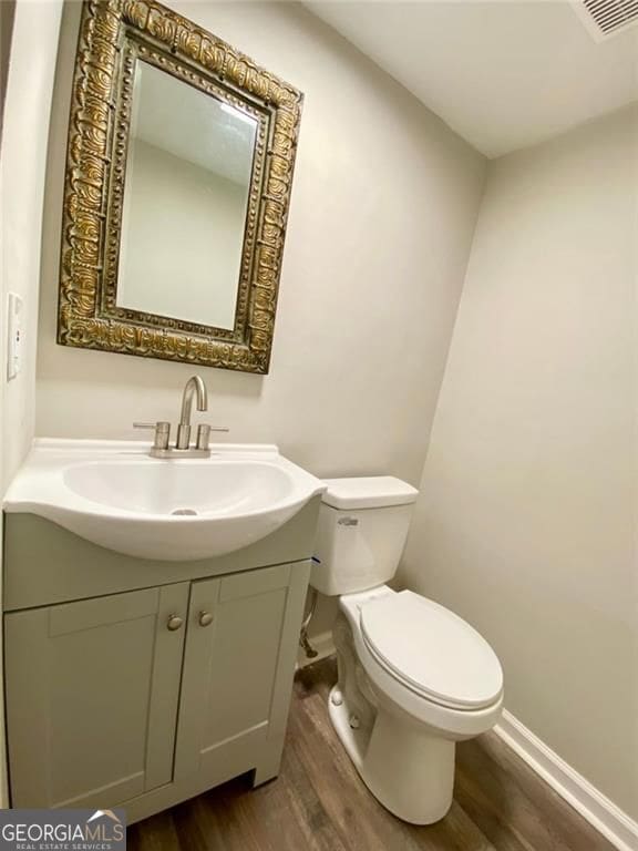 bathroom with wood-type flooring, toilet, and vanity