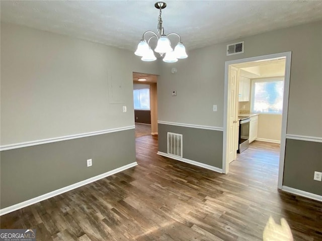 unfurnished dining area with hardwood / wood-style flooring and a chandelier