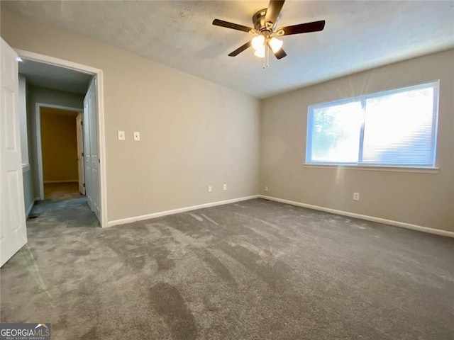 spare room featuring dark carpet and ceiling fan