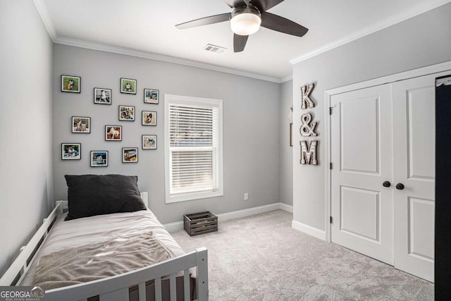 carpeted bedroom with ornamental molding, ceiling fan, and a closet