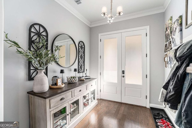 foyer entrance with french doors, ornamental molding, dark hardwood / wood-style floors, and an inviting chandelier