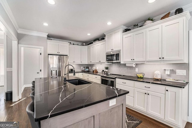 kitchen featuring an island with sink, appliances with stainless steel finishes, sink, and white cabinets